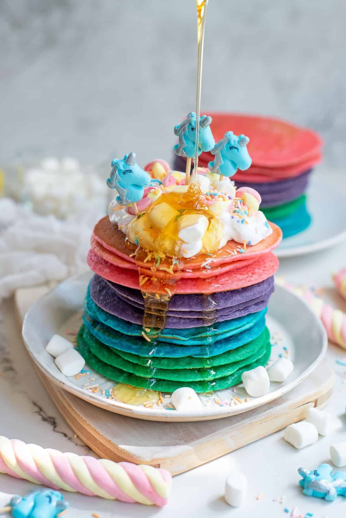 Pilha de panquecas de unicórnio com mel derramado sobre elas.