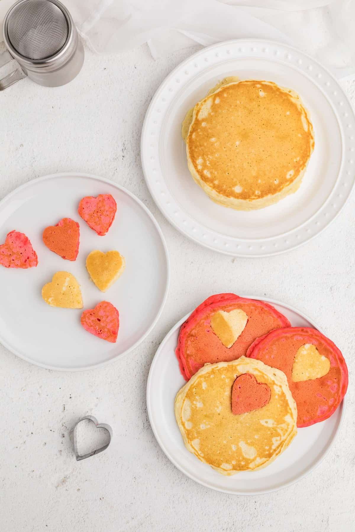 Visão aérea de panquecas cor-de-rosa e brancas com cortes em forma de coração.