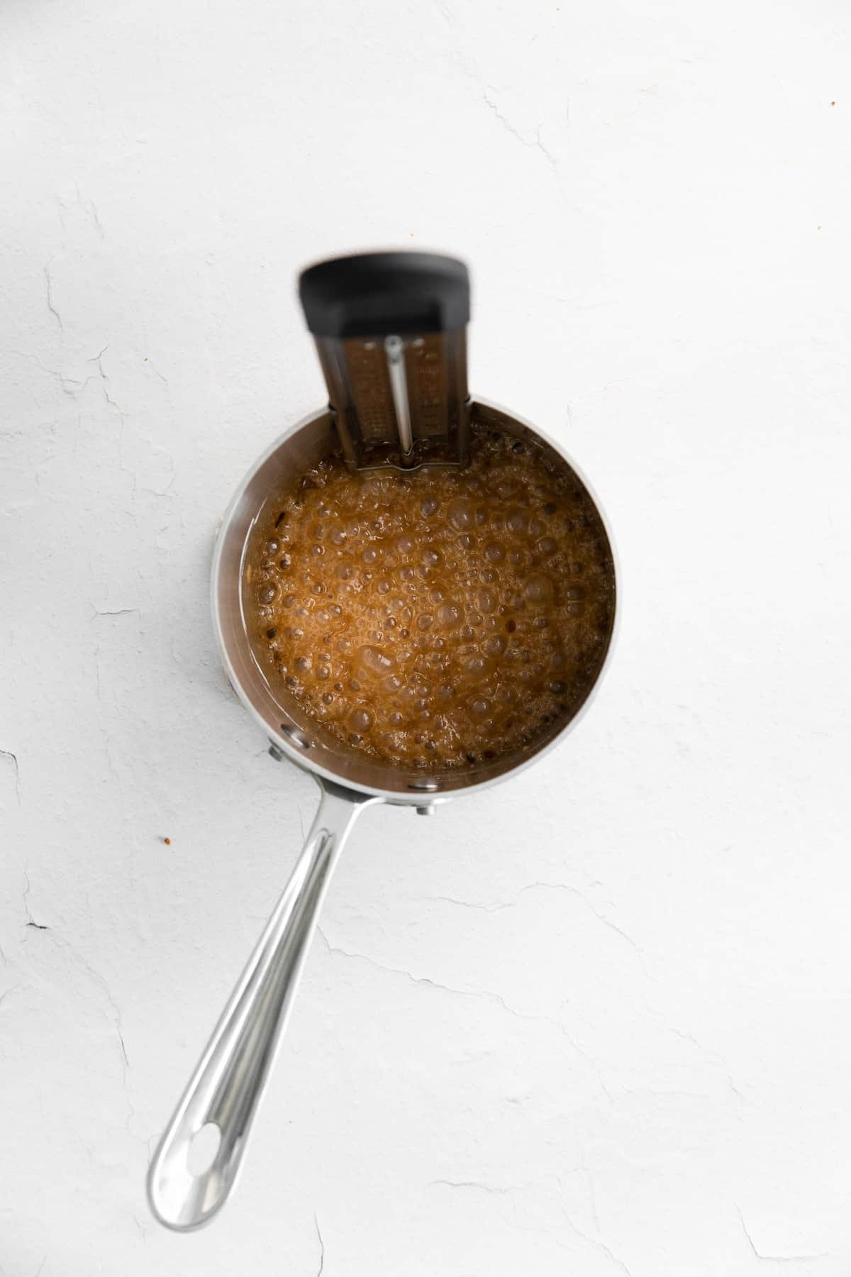 Caramelo cozinhando em uma pequena panela de metal.