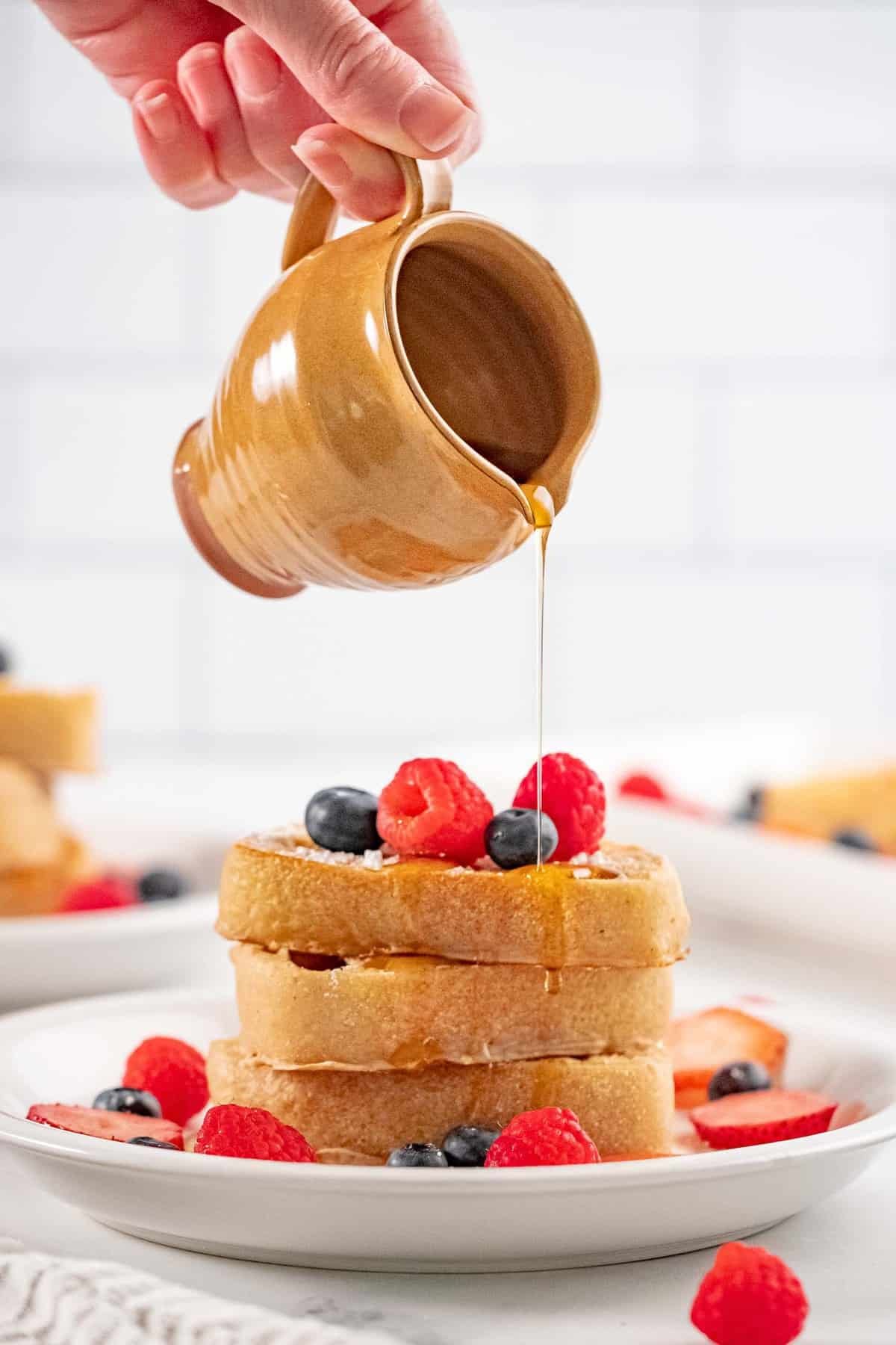 Xarope sendo derramado em um empilhamento de panquecas veganas.