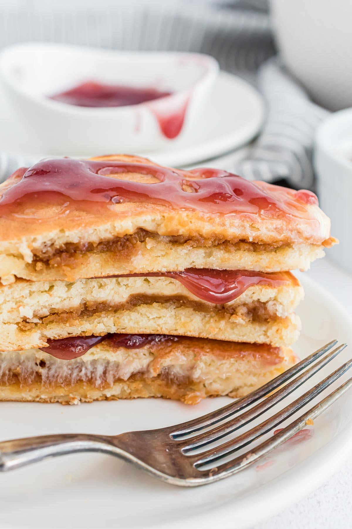 Panquecas cortadas para mostrar recheio de manteiga de amendoim e cobertura de geleia.