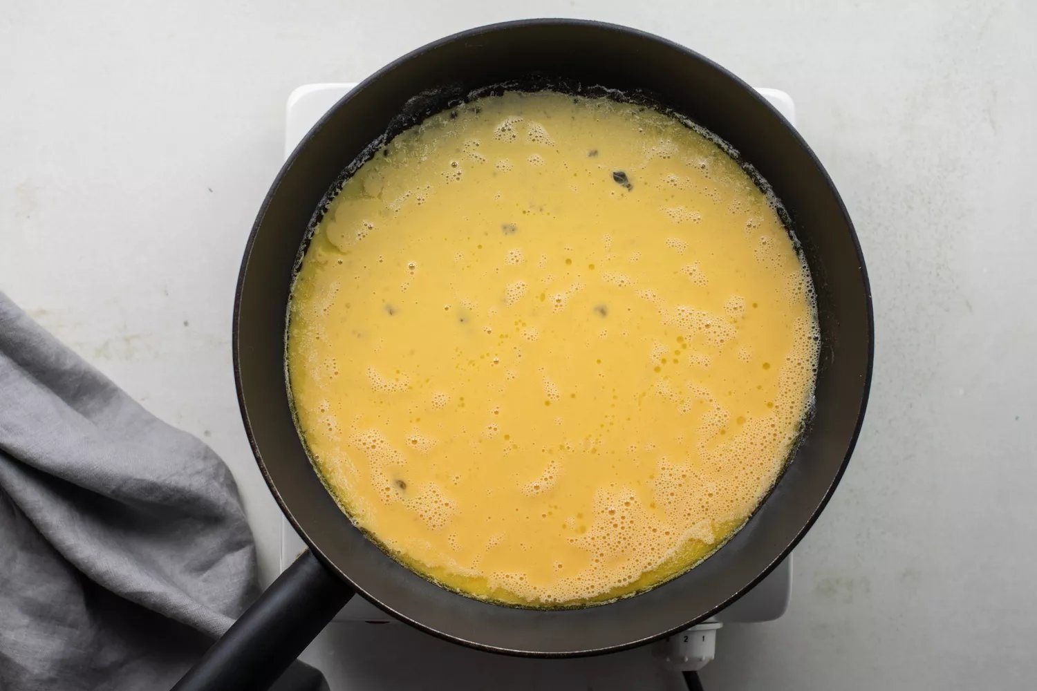 Beaten eggs covering the bottom of the frying pan