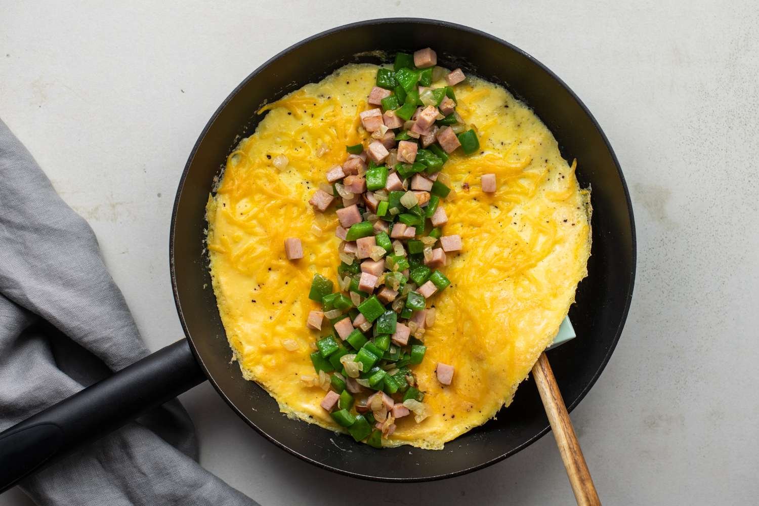 Ham and bell pepper filling spread in the center of the omelet