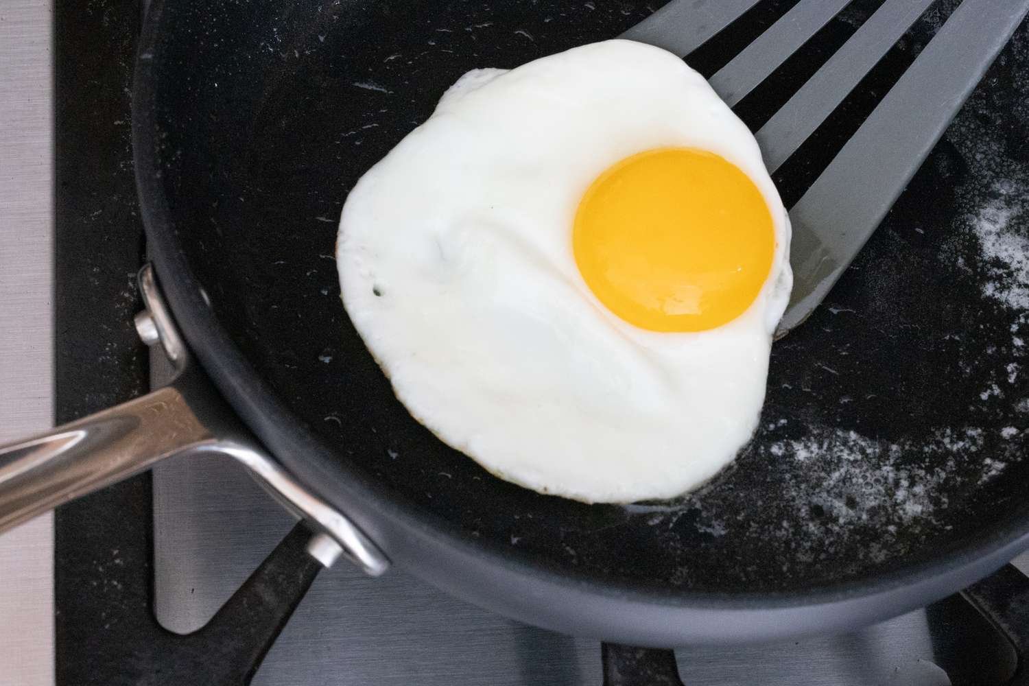 Spatula sliding under the egg in the skillet