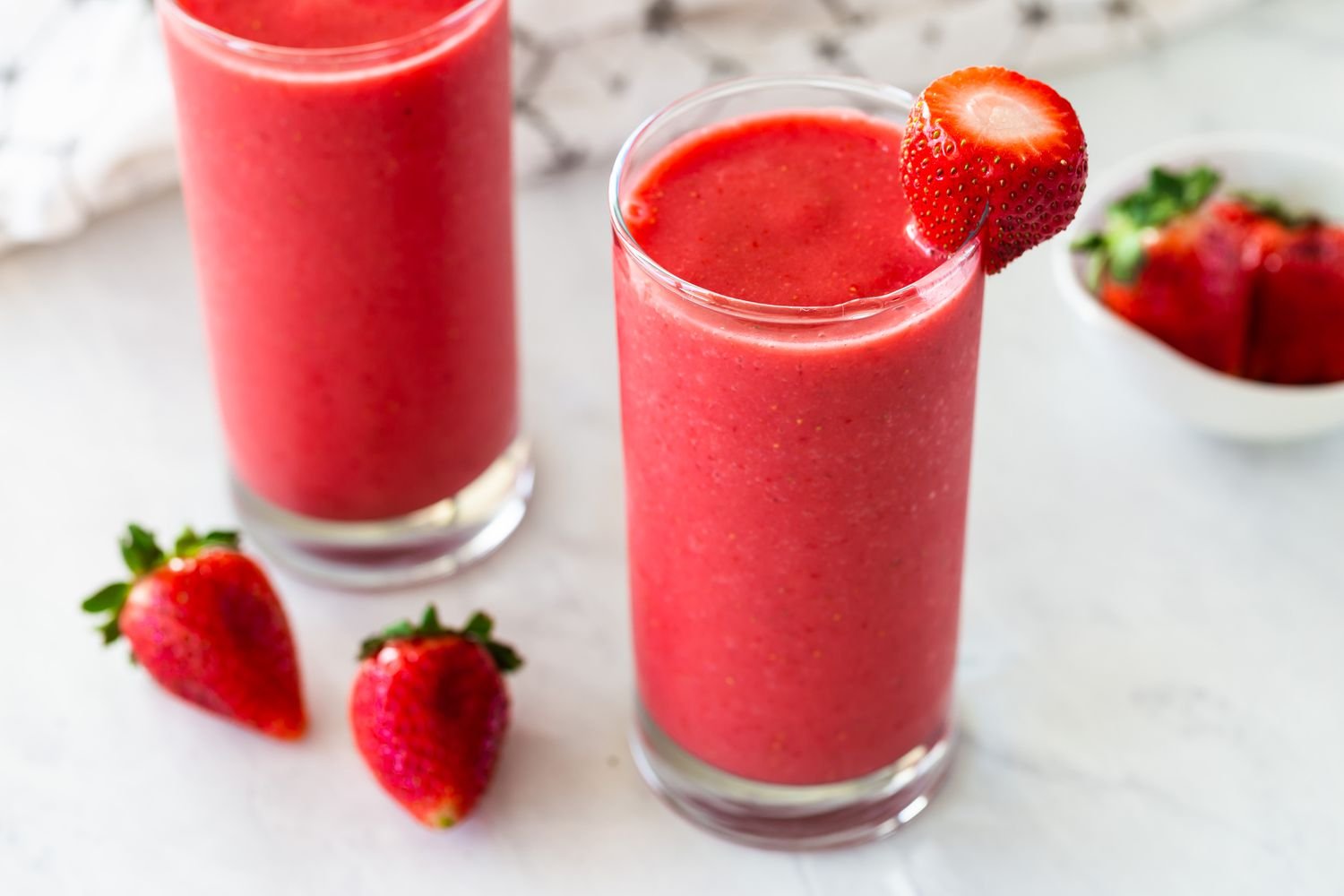 Strawberry smoothies in two glasses garnished with strawberries