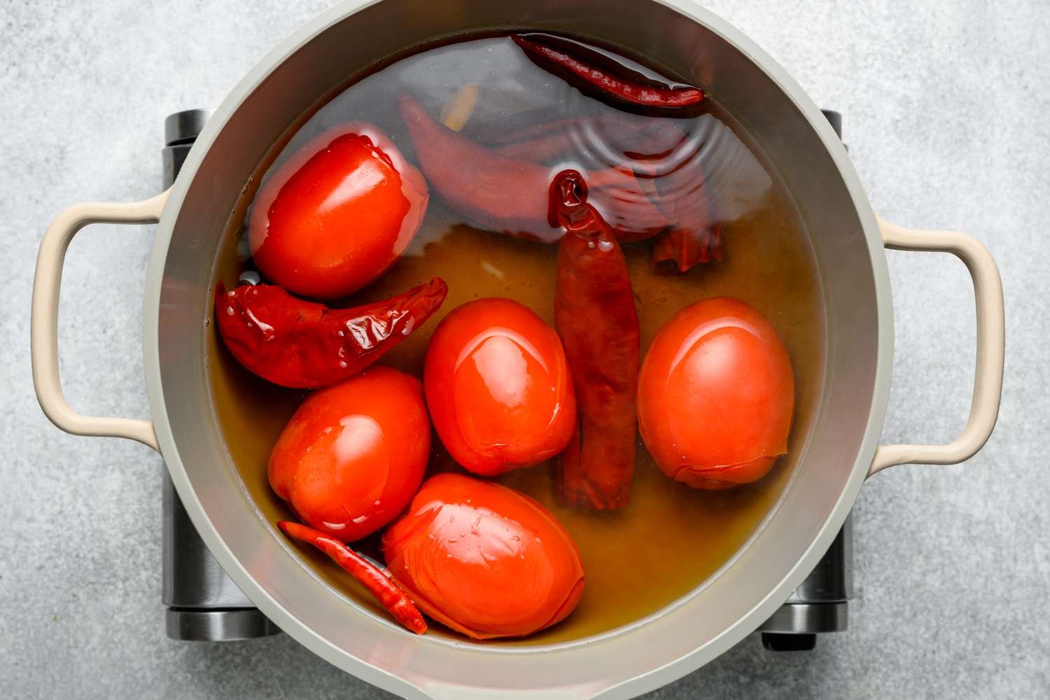 A pot of water with guajillo chiles, chile de arbol, Roma tomatoes, and garlic