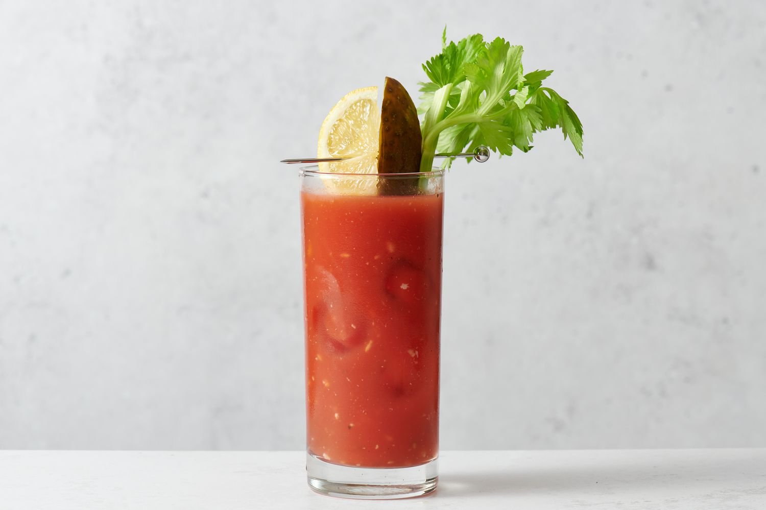A Bloody Mary garnished with a celery stick, pickle, and lemon wedge