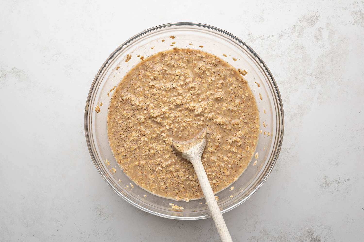 Oat mixture in a bowl with a wooden spoon