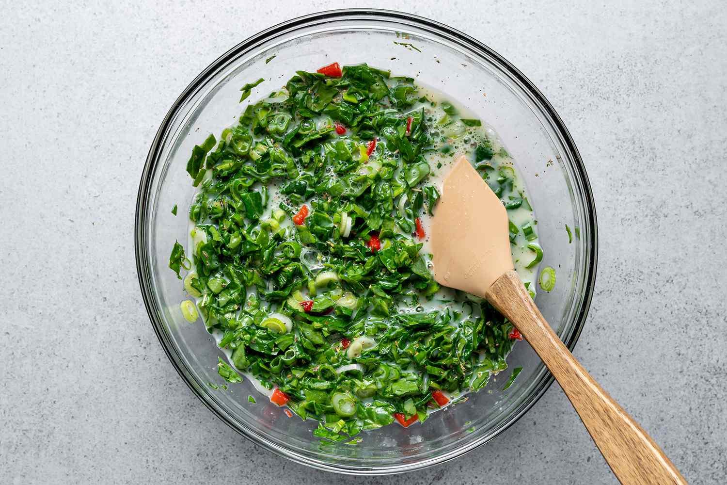Adding chopped spinach, roasted red peppers, green onions, salt, pepper, and Italian seasoning to the egg white mixture