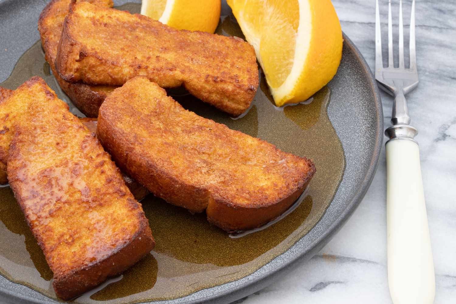 air fryer french toast on plate with orange wedge and maple syrup