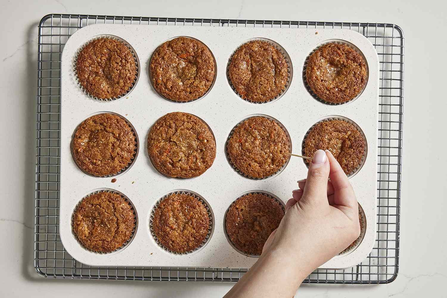 Muffins from oven being tested with a toothpick