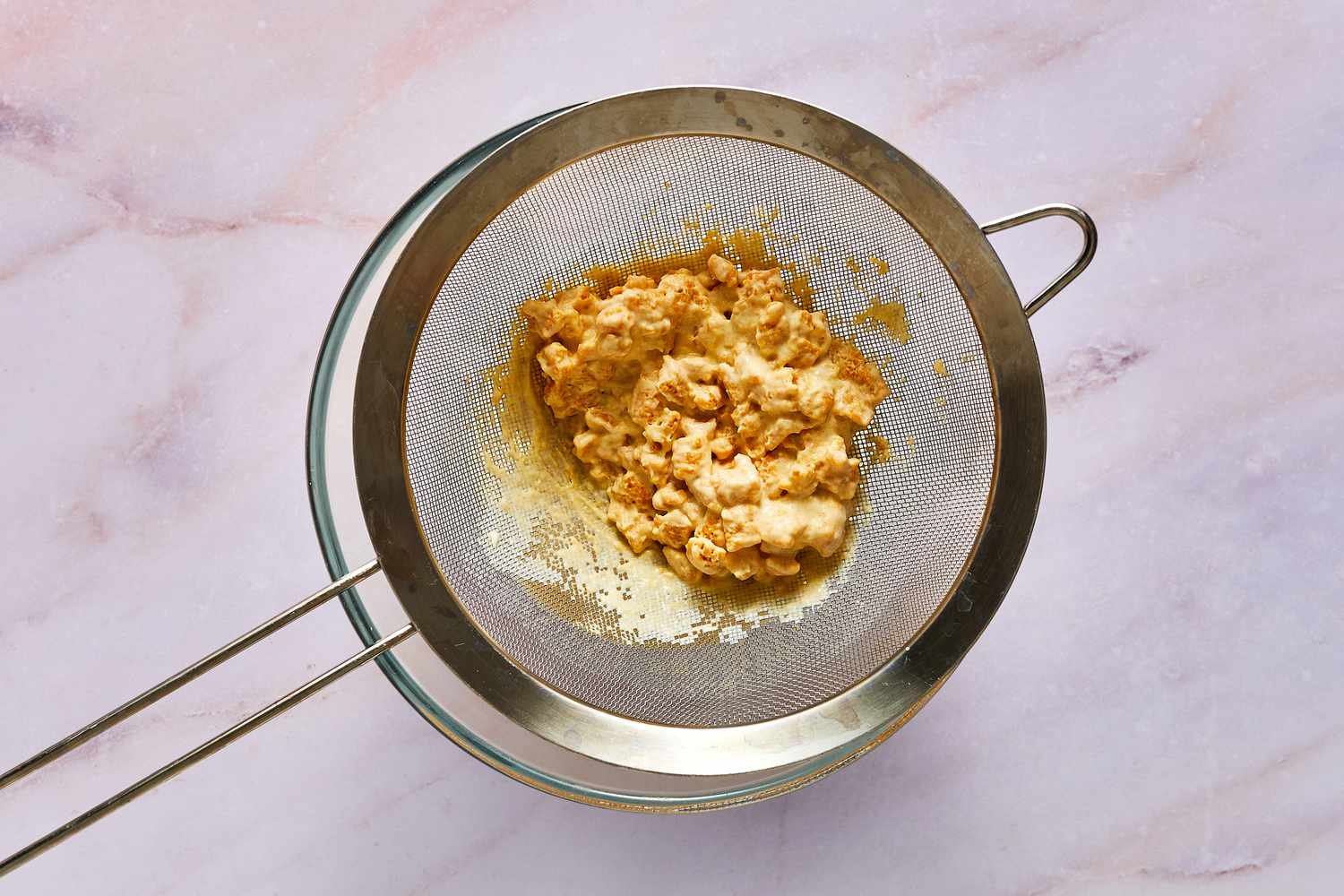 A strainer with soaked Cap'n Crunch cereal