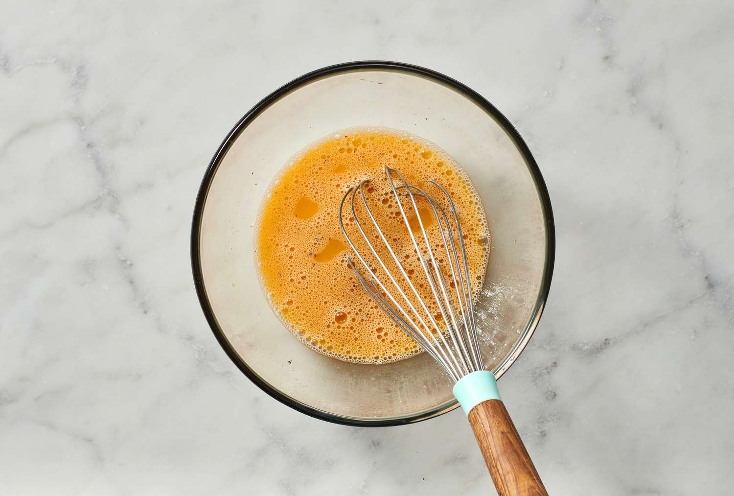 A bowl of beaten eggs with salt and pepper