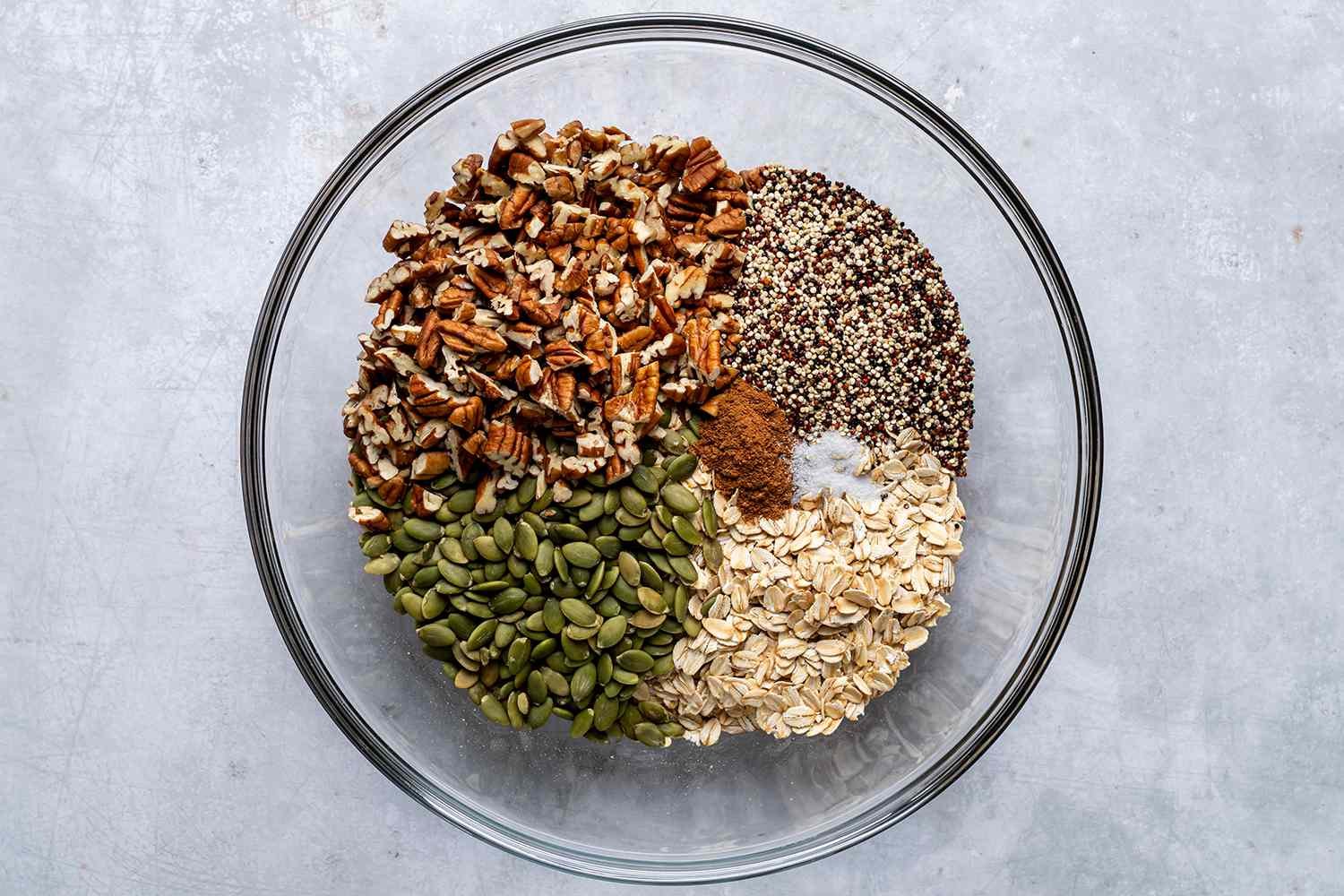 oats, pumpkin seeds, pecans, quinoa, and spices in a bowl
