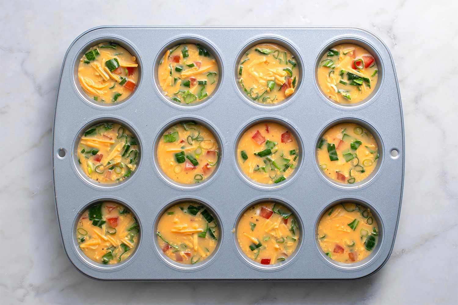 Egg and vegetable mixture poured into greased muffin tins