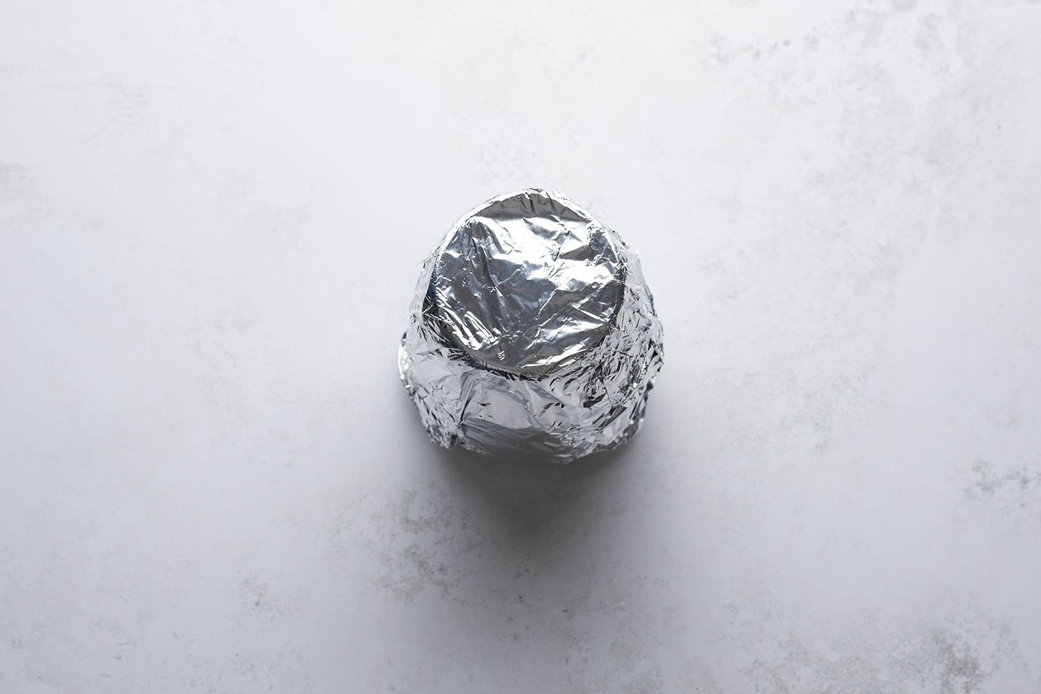 Glass container with lemon mixture covered in foil