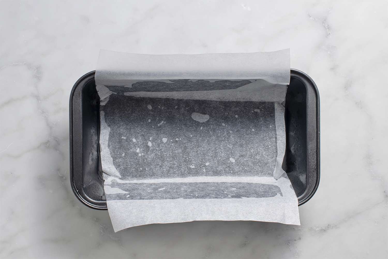 Greased loaf pan with parchment paper