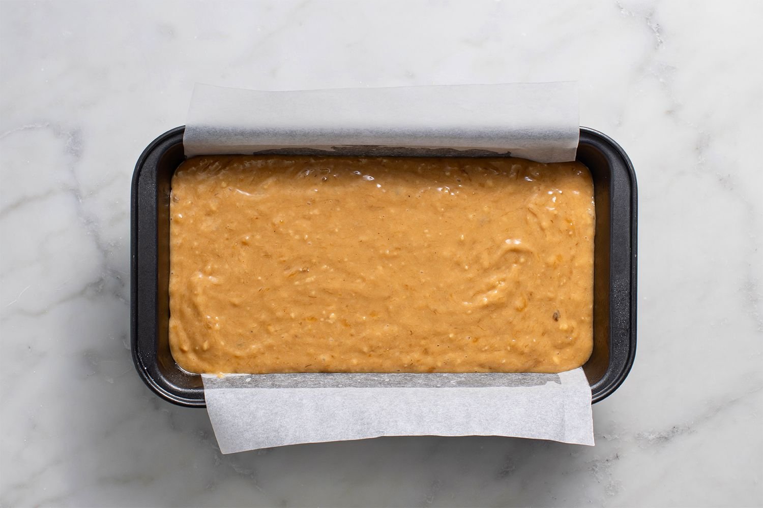 Batter in a lined loaf pan ready for the oven