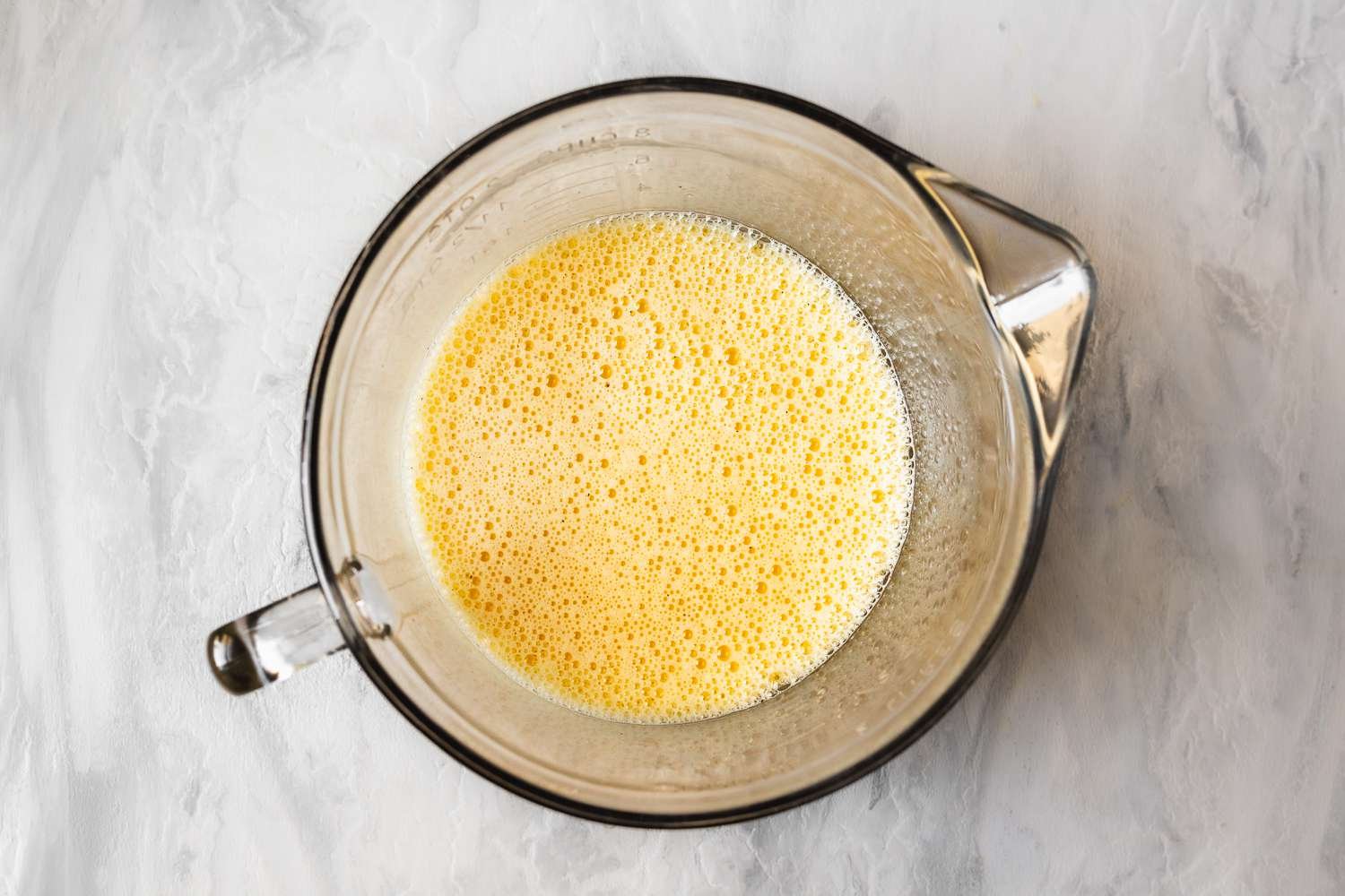 Milk added to eggs in measuring cup and whisked until foamy