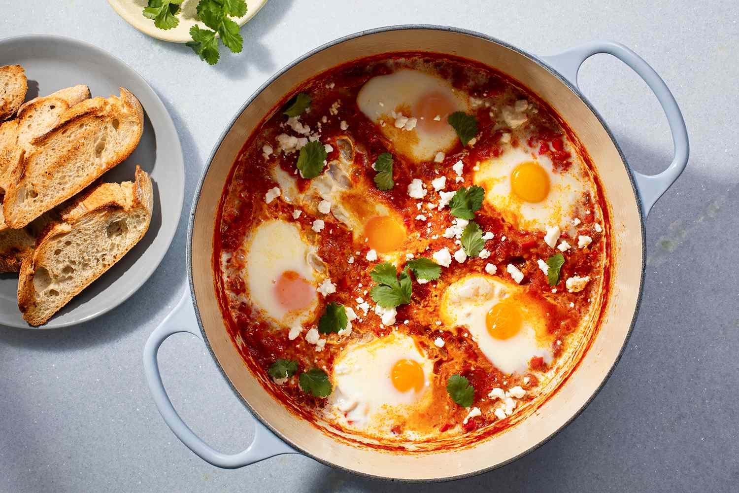 Shakshuka served in a pot with toasted bread on the side
