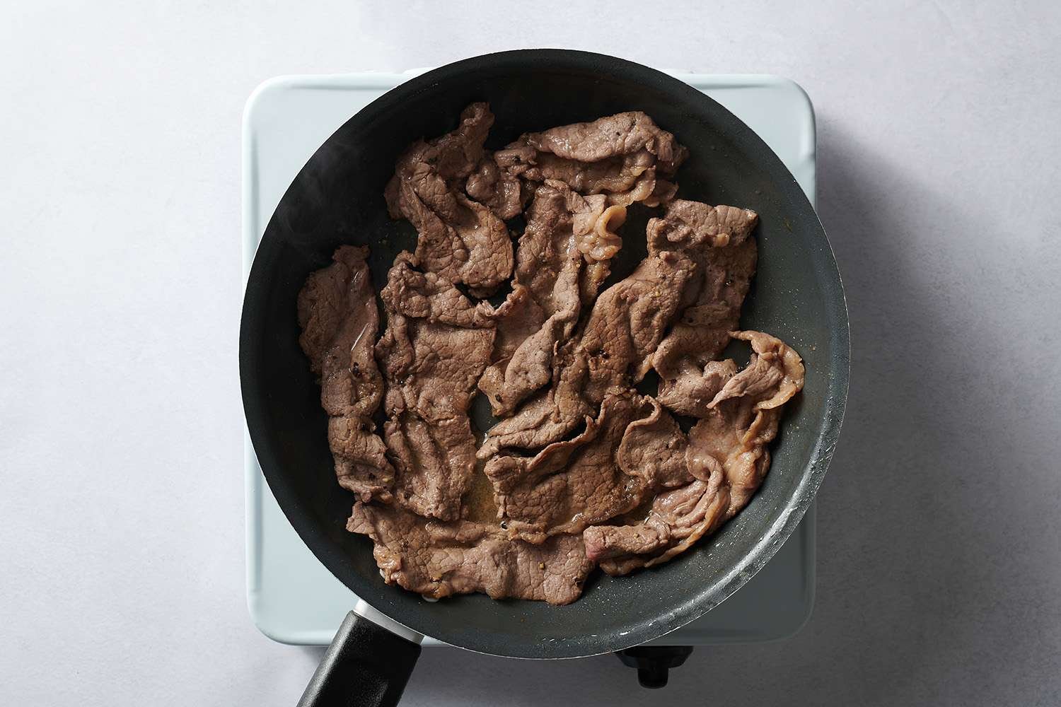 sliced beef cooking in skillet