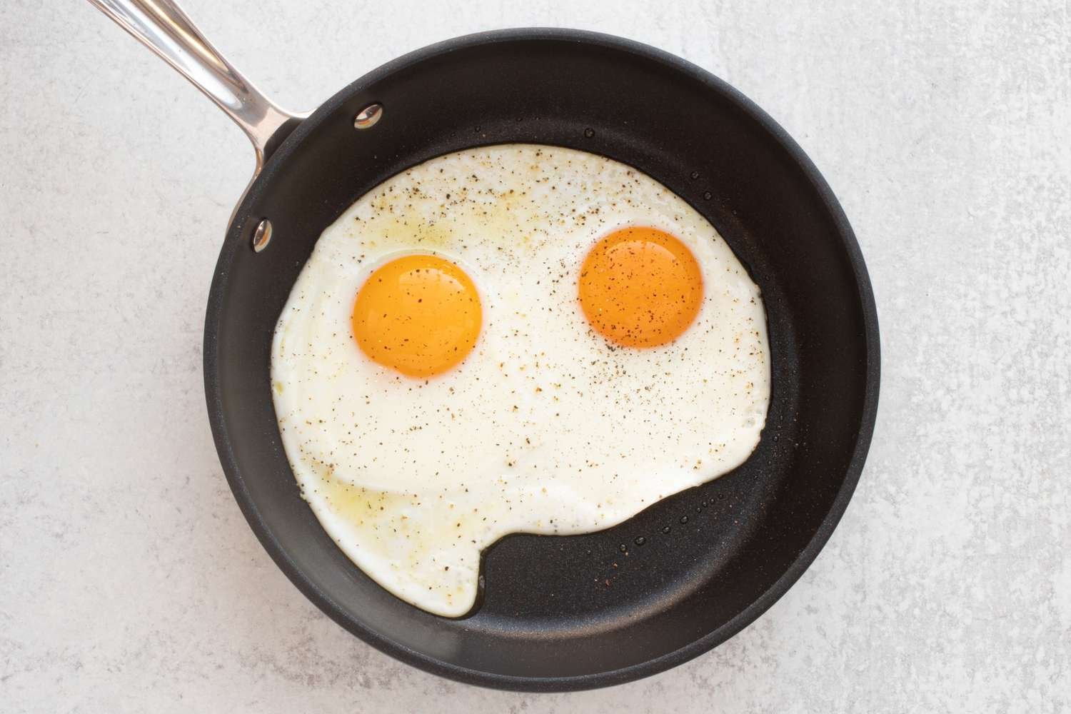 Two sunny-side up eggs in a small nonstick skillet.