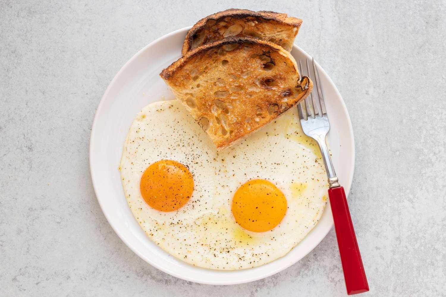 Two sunny-side up eggs on a plate with toast.