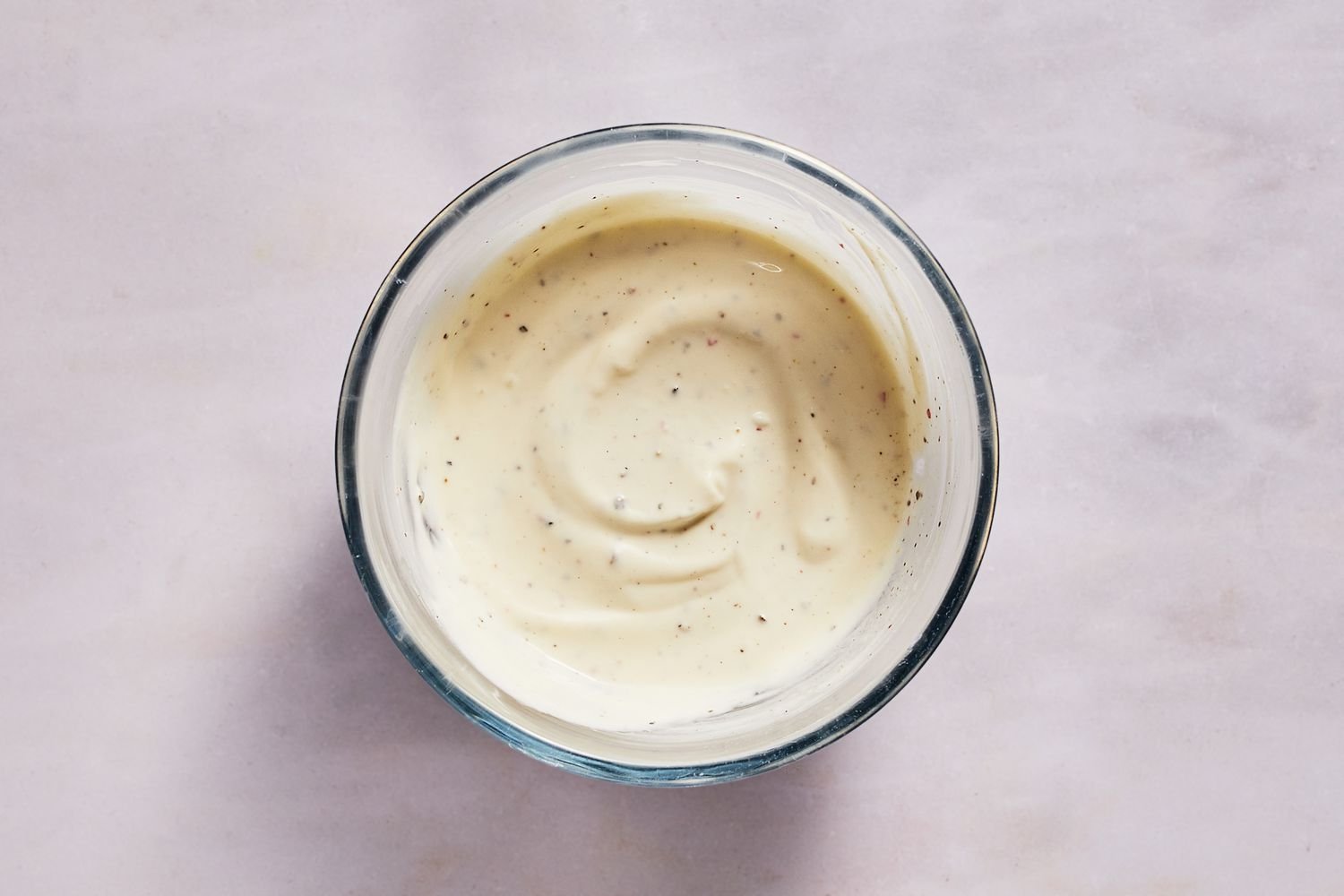 A small bowl of mayonnaise, Mexican crema, lime juice, salt, and black pepper