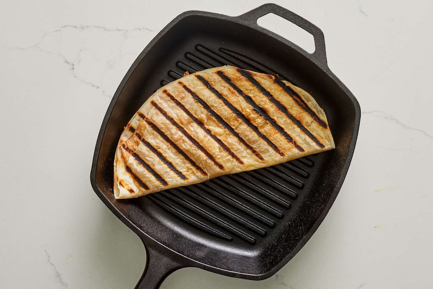 A folded quesadilla in a grill pan