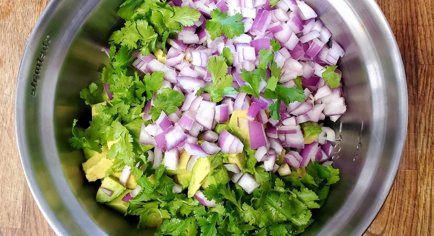 Mixing cucumbers, onions, cilantro, and avocado