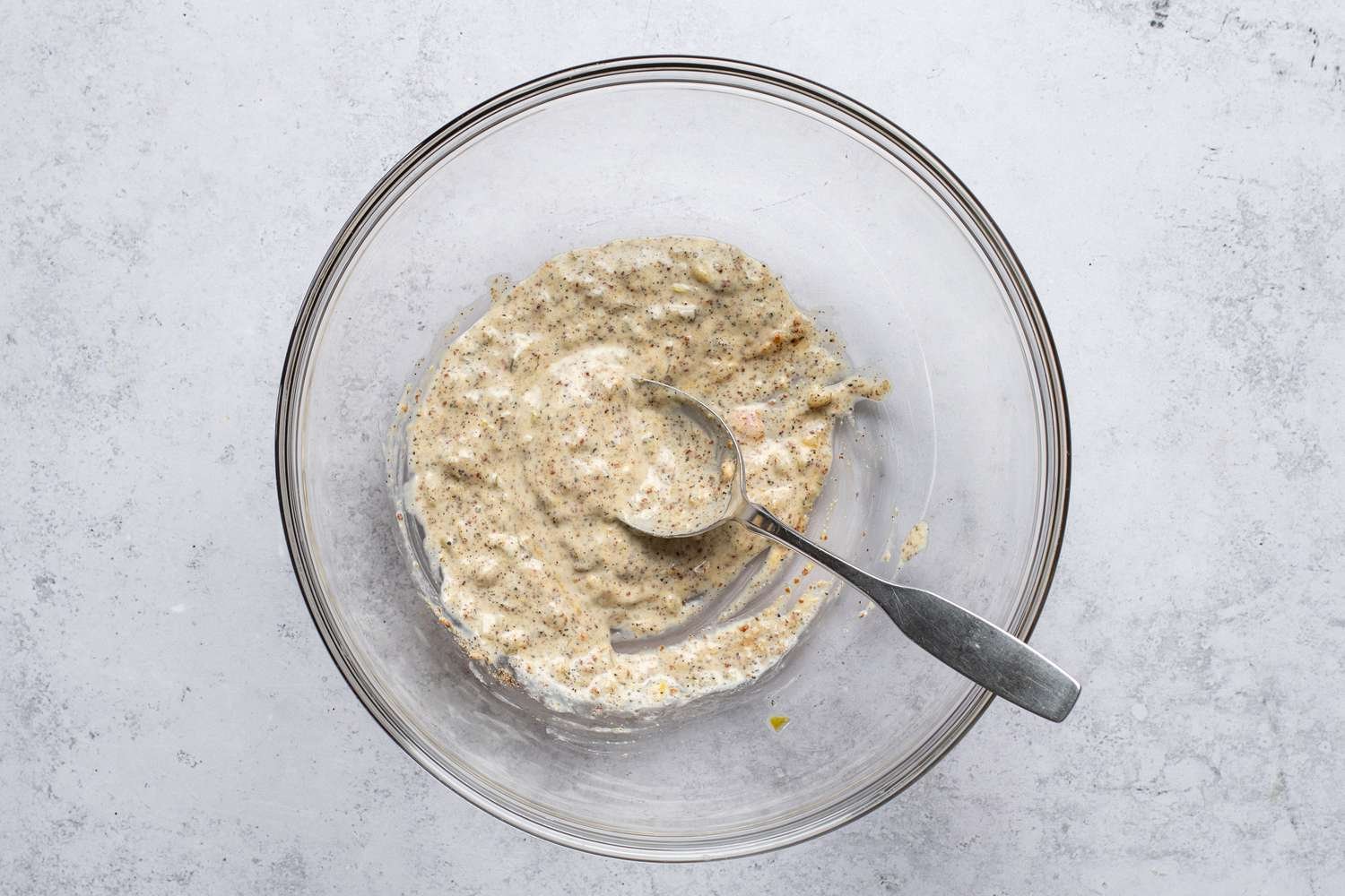 Mayo, relish, mustard, and salt and pepper in a bowl, with a spoon