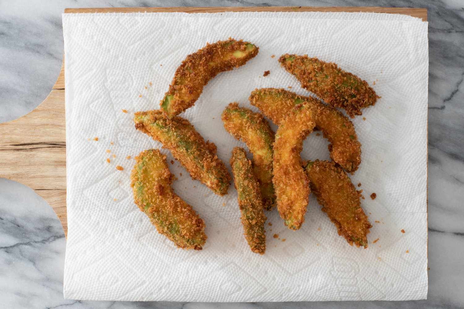 deep fried avocado wedges draining on paper towels