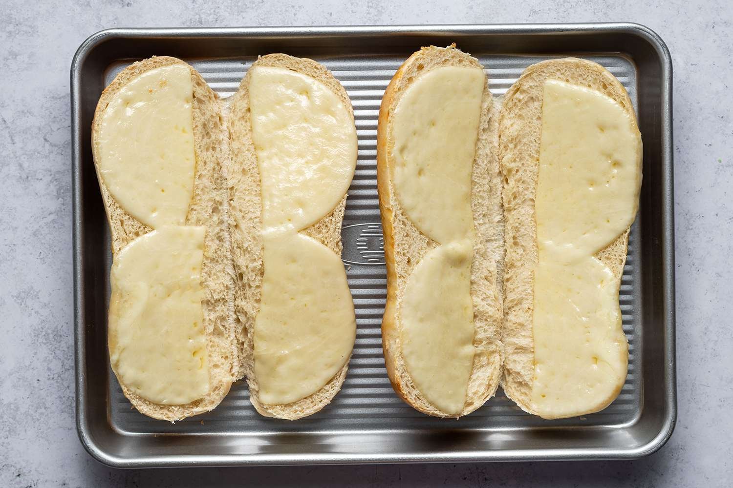 Two sliced rolls with melted cheese